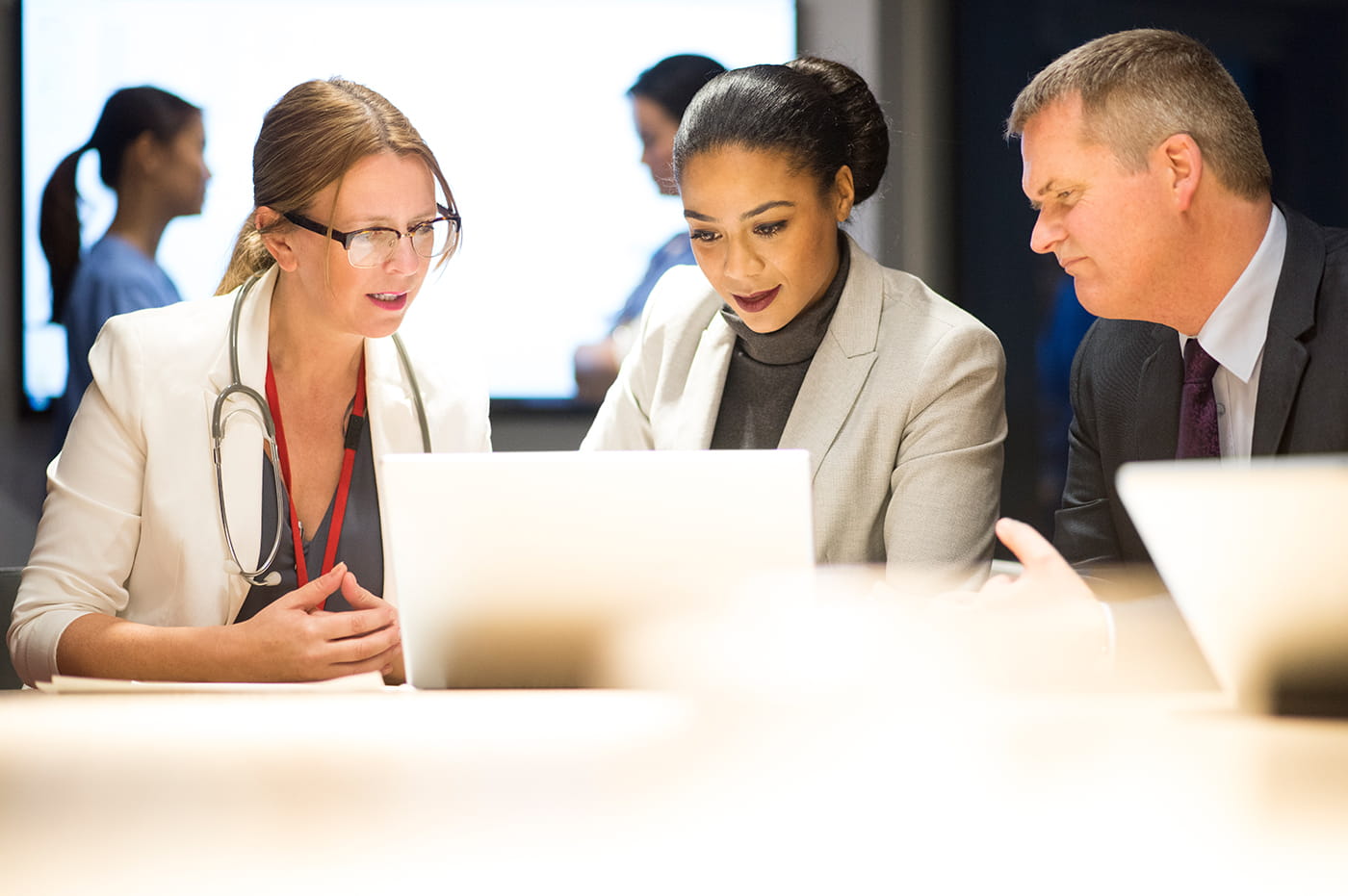 Two woman and man looking at a laptop device in a meeting