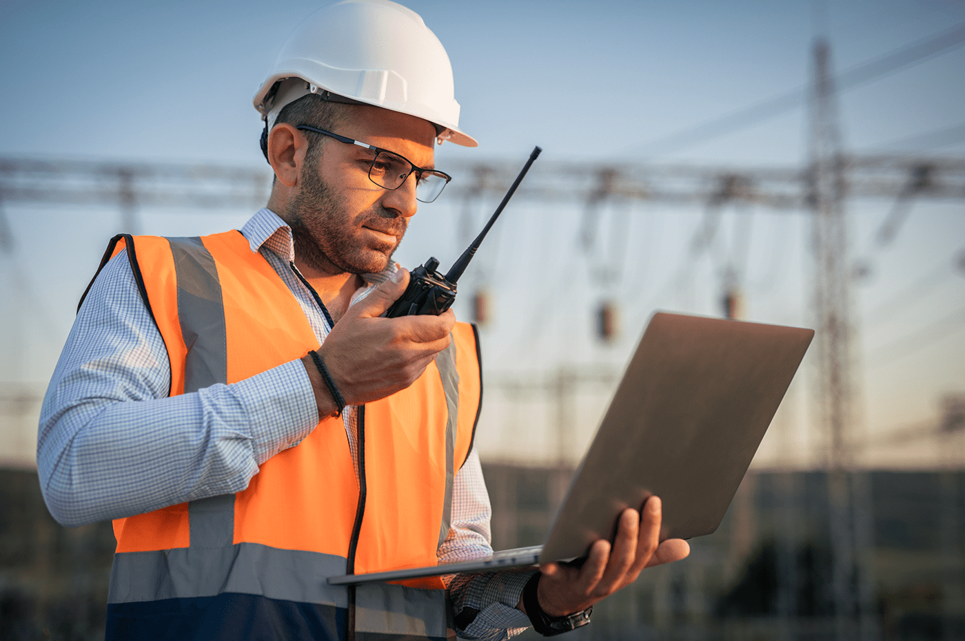 Construction worker holding a clipboard talking into a walkie talkie